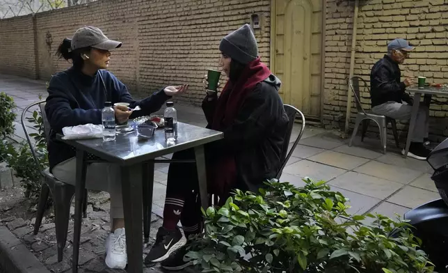 People drink tea in the alfresco dining area of a cafe in northern Tehran, Iran, Thursday, Nov. 7, 2024. (AP Photo/Vahid Salemi)