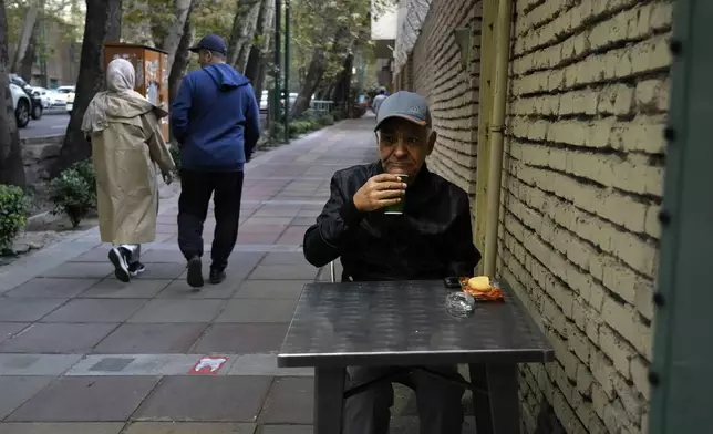 A man drinks tea in the alfresco dining area of a cafe in northern Tehran, Iran, Thursday, Nov. 7, 2024. (AP Photo/Vahid Salemi)