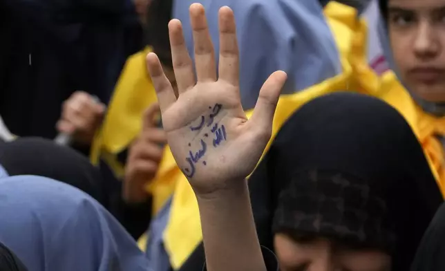 An Iranian schoolgirl holds up her hand with a sign reading in Farsi: "Lebanon's Hezbollah" in an annual rally in front of the former U.S. Embassy in Tehran, Iran, Sunday, Nov. 3, 2024, marking the 45th anniversary of Iranian students' takeover of the embassy, starting a hostage crisis. (AP Photo/Vahid Salemi)