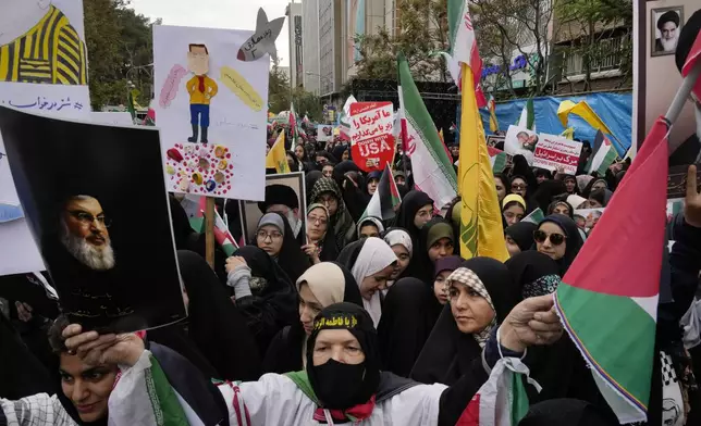 An Iranian demonstrator holds a poster of the slain Hezbollah leader, Hassan Nasrallah, and a Palestinian flag in an annual rally in front of the former U.S. Embassy in Tehran, Iran, Sunday, Nov. 3, 2024, marking the 45th anniversary of Iranian students' takeover of the embassy, starting a hostage crisis. (AP Photo/Vahid Salemi)