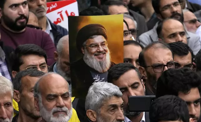 An Iranian demonstrator holds up a poster of the slain Hezbollah leader Hassan Nasrallah at the annual rally in front of the former U.S. Embassy in Tehran, Iran, Sunday, Nov. 3, 2024, marking the 45th anniversary of Iranian students' takeover of the embassy, starting a hostage crisis. (AP Photo/Vahid Salemi)