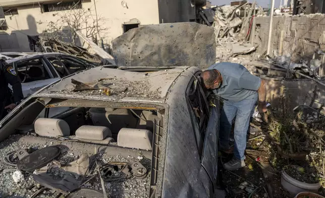 A man surveys damage to his car after projectiles fired from Lebanon hit a home in Tira, central Israel, Saturday, Nov. 2, 2024. (AP Photo/Ariel Schalit)