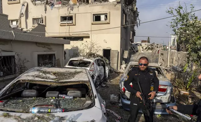 Israeli police men work at the site where projectiles fired from Lebanon hit a home in Tira, central Israel, Saturday, Nov. 2, 2024. (AP Photo/Ariel Schalit)