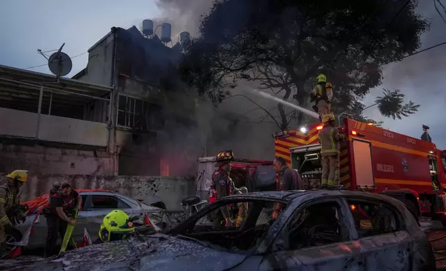 Firefighters work to extinguish a fire after a rocket fired from Lebanon hit Kiryat Ata, northern Israel, on Monday, Nov. 11, 2024. (AP Photo/Francisco Seco)