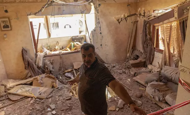 A local resident stands next to debris inside his house after it was struck by projectiles fired from Lebanon in Kfar Yasif, north west Israel, Saturday, Nov. 9, 2024. (AP Photo/Francisco Seco)