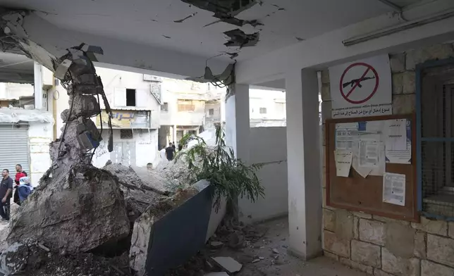 Palestinians pass by the rubble of the United Nations Office for helping Palestinian refugees, UNRWA, that was partly demolished during the Israeli army operation in the West Bank refugee camp of Nur Shams, in Tulkarem Thursday, Oct. 31, 2024. (AP Photo/Nasser Nasser)