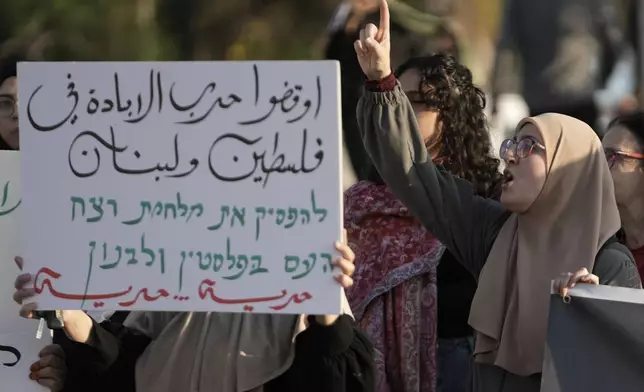 Palestinian citizens of Israel protest against Israel's military operations in the Gaza Strip and Lebanon, in Umm Al-Fahm, Israel, Saturday, Nov. 9, 2024. The placard in Arabic reads: " the war of extermination in Palestine and Lebanon - read more about this topic." (AP Photo/Mahmoud Illean)