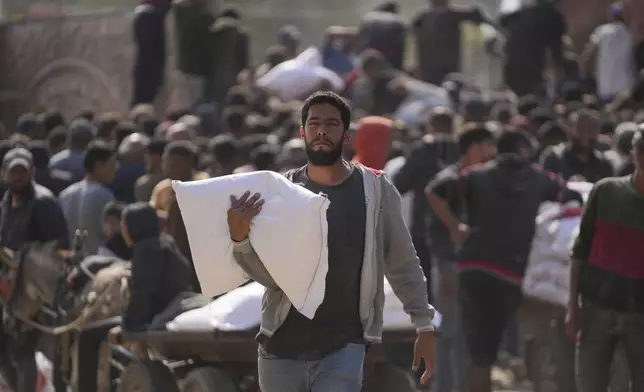 Palestinians gather to receive bags of flour distributed by UNRWA, the U.N. agency helping Palestinian refugees, in Deir al Balah, central Gaza Strip, Saturday, Nov. 2, 2024. (AP Photo/Abdel Kareem Hana)