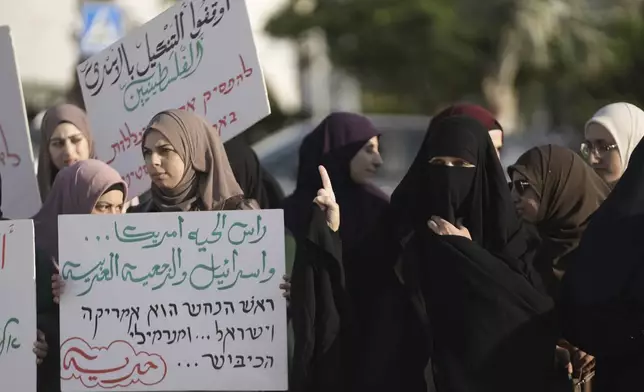 Palestinian citizens of Israel protest against Israel's military operations in the Gaza Strip and Lebanon, in Umm Al-Fahm, Israel, Saturday, Nov. 9, 2024. The placard in Arabic reads: "the head of the snake is America, Israel and Arab reactionaries." (AP Photo/Mahmoud Illean)