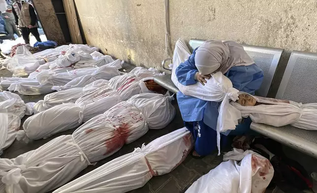 FILE - A Palestinian woman reacts over the body of a child as she sits by bodies of Palestinians killed by Israeli airstrikes on Jabaliya refugee camp, at the Indonesian hospital, northern Gaza Strip, Nov. 18, 2023. (AP Photo/Ahmed Alarini, File)