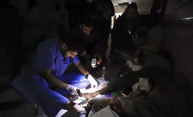 FILE - Palestinian medics treat a wounded person using torchlights after running out of power at the Indonesian hospital in Beit Lahiya during the ongoing bombardment of the northern Gaza Strip, Nov. 19, 2023. (AP Photo/Ahmed Alarini, File)