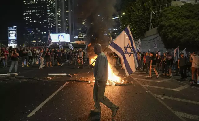 Israelis light a bonfire during a protest after Prime Minister Benjamin Netanyahu has dismissed his popular defense minister Yoav Gallant, in Tel Aviv, Israel, Tuesday, Nov. 5, 2024. (AP Photo/Oded Balilty)