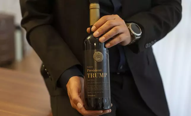 Israel Ganz, chairman of the Yesha settlers council and head of the Mateh Binyamin Regional Council, poses for a portrait holding a bottle of wine bearing the name of U.S. President-elect Donald Trump in the Shaar Binyamin Industrial Park in the West Bank, Monday, Nov. 11, 2024. (AP Photo/Ohad Zwigenberg)