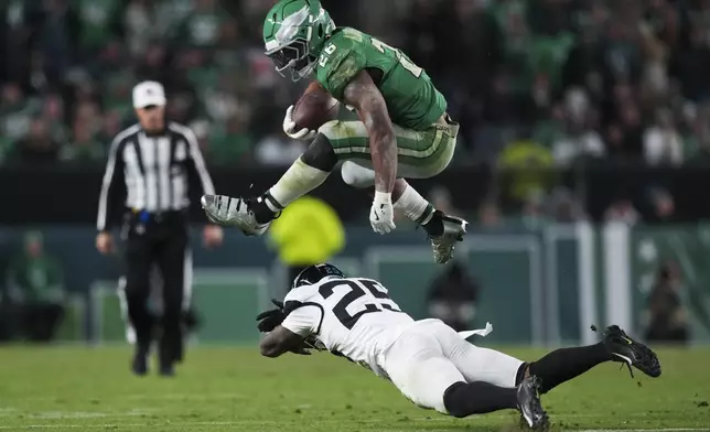 Philadelphia Eagles running back Saquon Barkley (26) leaps over Jacksonville Jaguars cornerback Ronald Darby (25) during the second half of an NFL football game Sunday, Nov. 3, 2024, in Philadelphia. (AP Photo/Matt Slocum)