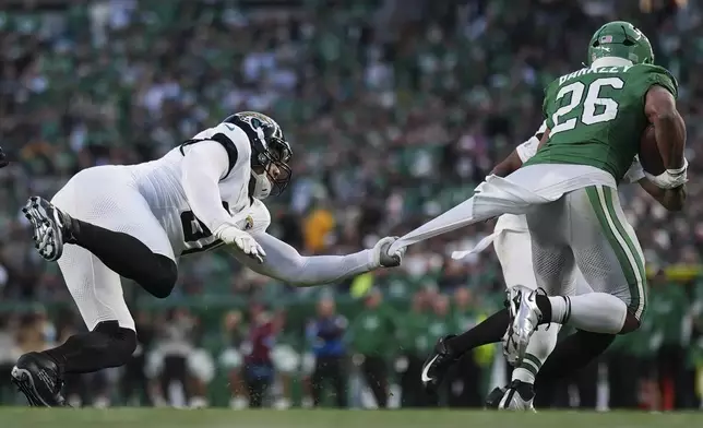 Jacksonville Jaguars defensive end Arik Armstead (91) holds on to Philadelphia Eagles running back Saquon Barkley (26) during the first half of an NFL football game Sunday, Nov. 3, 2024, in Philadelphia. (AP Photo/Matt Slocum)