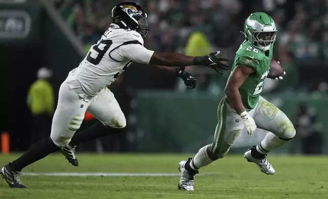 Philadelphia Eagles running back Saquon Barkley (26) gets past Jacksonville Jaguars defensive end Myles Cole (59) during the second half of an NFL football game Sunday, Nov. 3, 2024, in Philadelphia. (AP Photo/Matt Slocum)