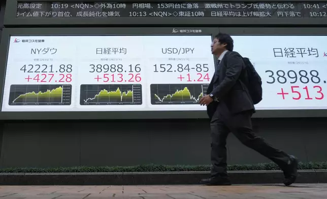 A man walks past an electronic stock board showing Japan's Nikkei 225 index, second left, at a securities firm Wednesday, Nov. 6, 2024 in Tokyo.(AP Photo/Shuji Kajiyama)