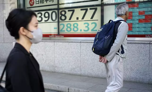 Person walk in front of an electronic stock board showing Japan's Nikkei index at a securities firm Wednesday, Nov. 13, 2024, in Tokyo. (AP Photo/Eugene Hoshiko)