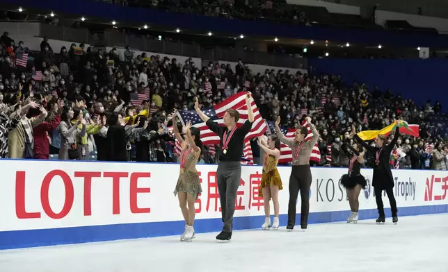 Gold medalists Madison Chock and Evan Bates of the U.S., left, silver medalists Christina Carreira and Anthony Ponomarenko of the U.S.,center, and bronze medalists Allison Reed and Saulius Ambrulevicius of Lithuania react with their flags after competing the ice dance segment at the Grand Prix of Figure Skating series competition in Tokyo, Saturday, Nov. 9, 2024. (AP Photo/Hiro Komae)