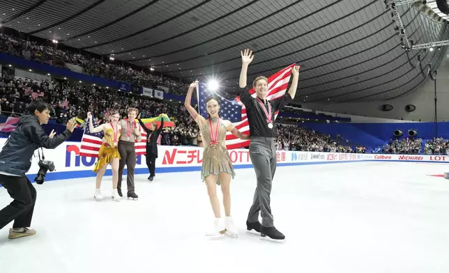 gold medalists Madison Chock and Evan Bates of the U.S. silver medalists Christina Carreira and Anthony Ponomarenko of the U.S., left, and bronze medalists Allison Reed and Saulius Ambrulevicius of Lithuania react with their flags after competing the ice dance segment at the Grand Prix of Figure Skating series competition in Tokyo, Saturday, Nov. 9, 2024. (AP Photo/Hiro Komae)