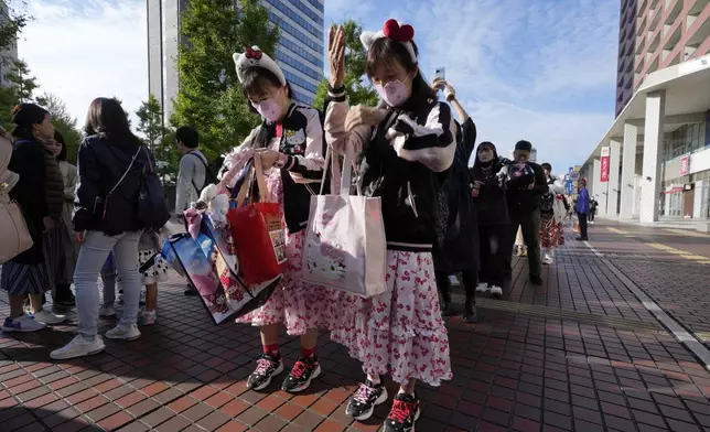 Hello Kitty fans put some character items on as they wait in line before entering Sanrio Puroland to celebrate its best known character's 50th birth anniversary, in Tama, a western suburb of Tokyo, Japan, Friday, Nov. 1, 2024. (AP Photo/Hiro Komae)