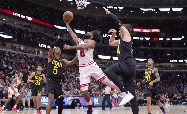 Chicago Bulls' Coby White (0) drives to the basket between Utah Jazz's Cody Williams (5) and Walker Kessler during the first half of an NBA basketball game Monday, Nov. 4, 2024, in Chicago. (AP Photo/Charles Rex Arbogast)