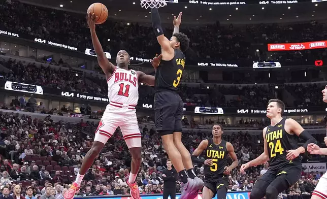 Chicago Bulls' Ayo Dosunmu (11) scores past Utah Jazz's Keyonte George during the first half of an NBA basketball game Monday, Nov. 4, 2024, in Chicago. (AP Photo/Charles Rex Arbogast)