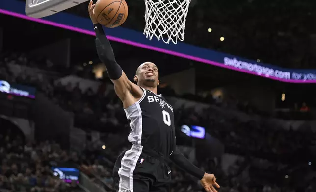 San Antonio Spurs' Keldon Johnson dunks during the first half of an NBA basketball game against the Utah Jazz, Saturday, Nov. 9, 2024, in San Antonio. (AP Photo/Darren Abate)