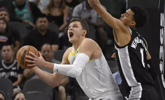 Utah Jazz center Walker Kessler, left, attempts to shoot as he is defended by San Antonio Spurs forward Victor Wembanyama during the first half of an NBA basketball game, Saturday, Nov. 9, 2024, in San Antonio. (AP Photo/Darren Abate)