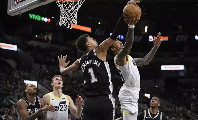 Utah Jazz's John Collins attempts to shoot against San Antonio Spurs' Victor Wembanyama (1) during the second half of an NBA basketball game, Saturday, Nov. 9, 2024, in San Antonio. Utah won 111-110. (AP Photo/Darren Abate)