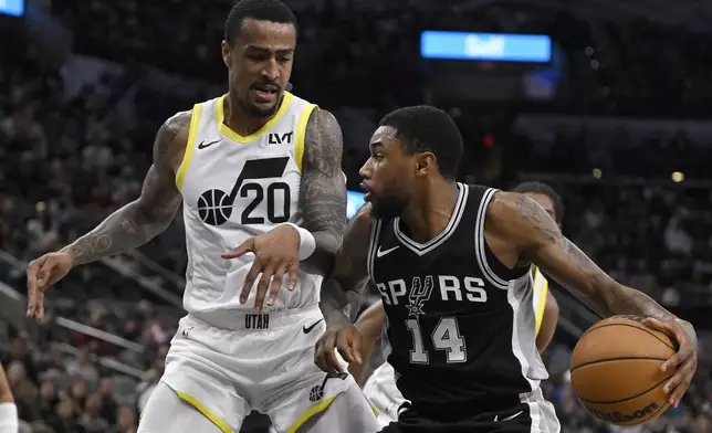 San Antonio Spurs' Blake Wesley (14) drives against Utah Jazz's John Collins during the first half of an NBA basketball game, Saturday, Nov. 9, 2024, in San Antonio. (AP Photo/Darren Abate)