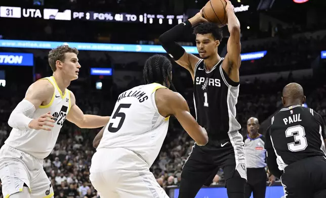 San Antonio Spurs' Victor Wembanyama (1) drives against Utah Jazz's Cody Williams (5) and Lauri Markkanen (23) during the first half of an NBA basketball game, Saturday, Nov. 9, 2024, in San Antonio. (AP Photo/Darren Abate)