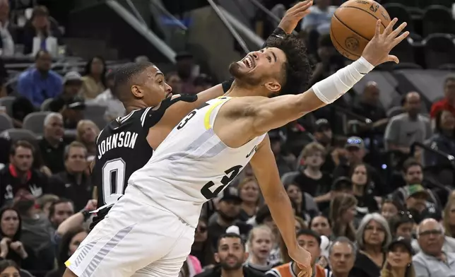 Utah Jazz's Johnny Juzang and San Antonio Spurs' Keldon Johnson (0) fight for possession during the second half of an NBA basketball game, Saturday, Nov. 9, 2024, in San Antonio. Utah won 111-110. (AP Photo/Darren Abate)