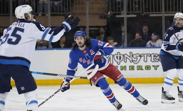 New York Rangers' Mika Zibanejad, center, watches as Winnipeg Jets' Mark Scheifele (55) knocks the puck down during the first period of an NHL hockey game Tuesday, Nov. 12, 2024, in New York. (AP Photo/Seth Wenig)