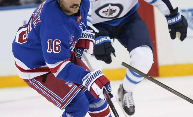 New York Rangers' Vincent Trocheck (16), left, moves the puck up the ice as Winnipeg Jets' Adam Lowry chases during the first period of an NHL hockey game Tuesday, Nov. 12, 2024, in New York. (AP Photo/Seth Wenig)