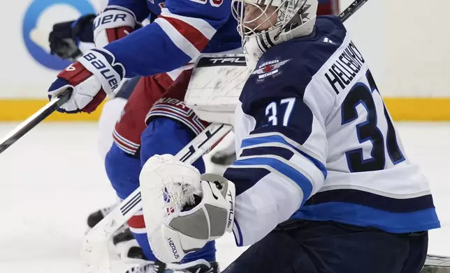 New York Rangers' Chris Kreider, top, and Winnipeg Jets goaltender Connor Hellebuyck watch as the puck passes nearby during the third period of an NHL hockey game Tuesday, Nov. 12, 2024, in New York. The Jets defeated the Rangers 6-3. (AP Photo/Seth Wenig)