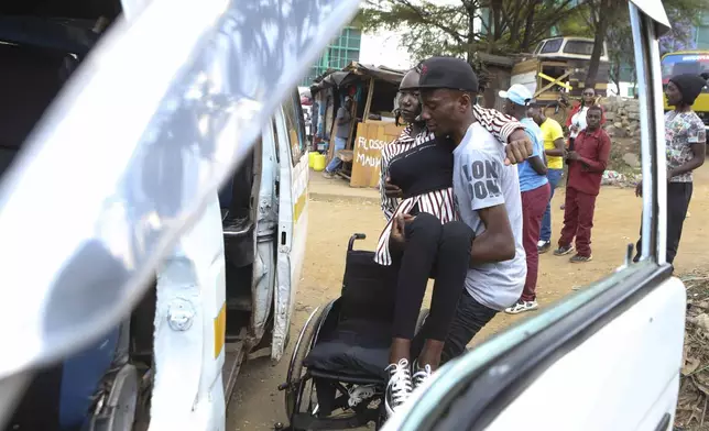 A man helps Carol Mwikali to get inside a public transport vehicle in Nairobi, Kenya, Wednesday, Oct. 9, 2024. (AP Photo/Andrew Kasuku)