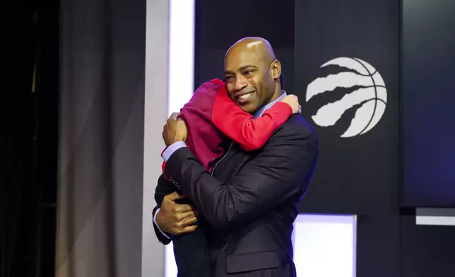 Former Toronto Raptors player Vince Carter hugs his son, Vince Carter Jr., after speaking to media ahead of his number retirement, before an NBA basketball game between the Toronto Raptors and the Sacramento Kings at the Scotiabank arena in Toronto on Saturday, Nov. 2, 2024. (Christopher Katsarov/The Canadian Press via AP)