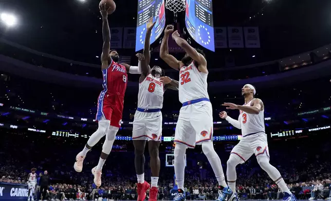 Philadelphia 76ers' Paul George (8) goes up for a shot against New York Knicks' OG Anunoby (8), Karl-Anthony Towns (32) and Josh Hart (3) during the first half of an Emirates NBA Cup basketball game, Tuesday, Nov. 12, 2024, in Philadelphia. (AP Photo/Matt Slocum)