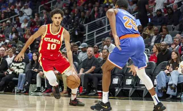 Atlanta Hawks forward Zaccharie Risacher (10) drives the lane while guarded by New York Knicks forward Mikal Bridges (25) during the first half of an NBA basketball game, Wednesday, Nov. 6, 2024, in Atlanta. (AP Photo/Jason Allen)