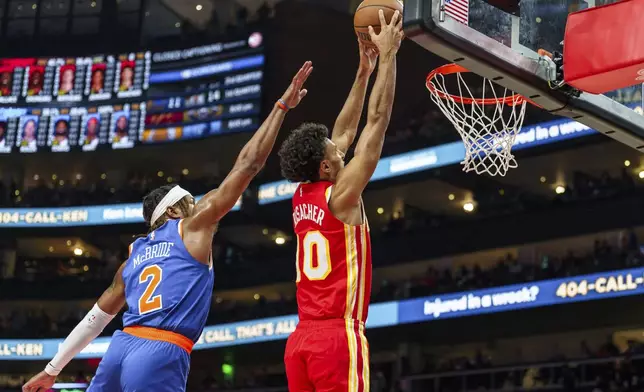 Atlanta Hawks forward Zaccharie Risacher (10) goes up for a slam dunk while guarded by New York Knicks guard Miles McBride (2) during the first half of an NBA basketball game, Wednesday, Nov. 6, 2024, in Atlanta. (AP Photo/Jason Allen)