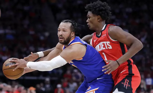 New York Knicks guard Jalen Brunson, left, tries to pass the ball as Houston Rockets forward Amen Thompson, right, reaches in during the first half of an NBA basketball game Monday, Nov. 4, 2024, in Houston. (AP Photo/Michael Wyke)