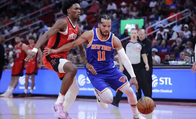 New York Knicks guard Jalen Brunson (11) drives to the basket around Houston Rockets forward Amen Thompson, left, during the first half of an NBA basketball game Monday, Nov. 4, 2024, in Houston. (AP Photo/Michael Wyke)