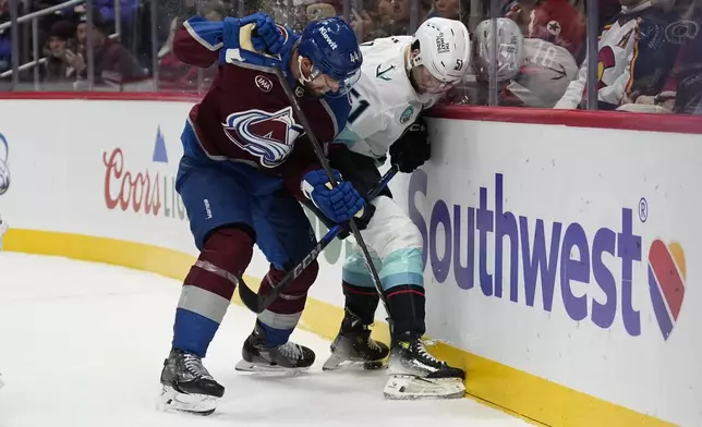 Colorado Avalanche defenseman Calvin de Haan (44) and Seattle Kraken center Shane Wright (51) battle on the boards during the second period of an NHL hockey game Tuesday, Nov. 5, 2024, in Denver. (AP Photo/Jack Dempsey)