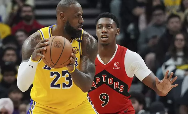 Los Angeles Lakers' LeBron James (23) protects the ball from Toronto Raptors' RJ Barrett (9) during the first half of an NBA basketball game in Toronto on Friday, Nov. 1, 2024. (Frank Gunn/The Canadian Press via AP)