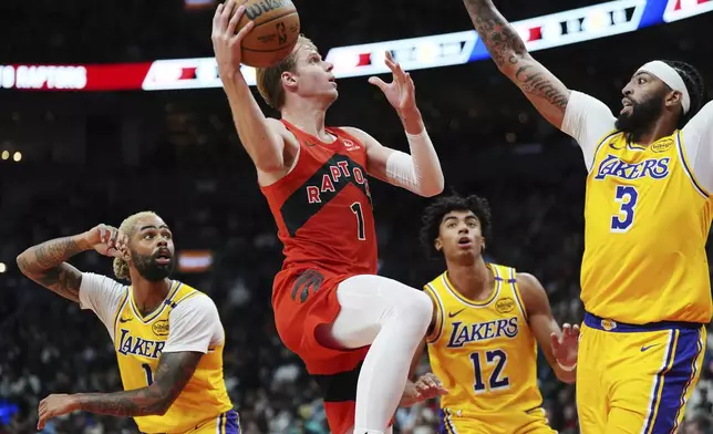 Toronto Raptors' Gradey Dick (1) shoots surrounded by Los Angeles Lakers' D'Angelo Russell (1), Max Christie (12) and Anthony Davis (3) during the first half of an NBA basketball game in Toronto on Friday, Nov. 1, 2024. (Frank Gunn/The Canadian Press via AP)