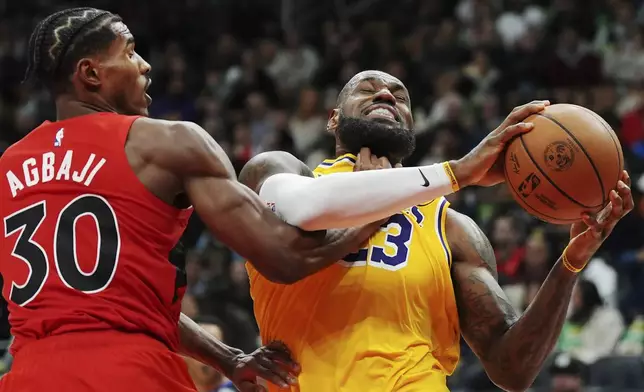 Toronto Raptors' Ochai Agbaji (30) fouls Los Angeles Lakers' LeBron James (23) during second half of an NBA basketball game in Toronto on Friday, Nov. 1, 2024. (Frank Gunn/The Canadian Press via AP)