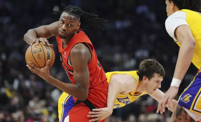 Toronto Raptors' Jonathan Mogbo, left, battles for the ball with Los Angeles Lakers' Austin Reaves, center, during the first half of an NBA basketball game in Toronto on Friday, Nov. 1, 2024. (Frank Gunn/The Canadian Press via AP)