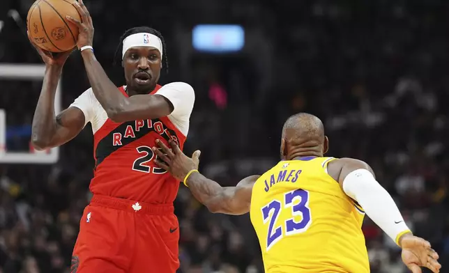 Toronto Raptors' Chris Boucher (25) protects the ball from Los Angeles Lakers' LeBron James (23) during the first half of an NBA basketball game in Toronto on Friday, Nov. 1, 2024. (Frank Gunn/The Canadian Press via AP)