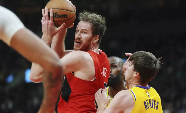 Toronto Raptors' Jakob Poeltl, left, protects the ball from Los Angeles Lakers' Austin Reaves during the first half of an NBA basketball game in Toronto on Friday, Nov. 1, 2024. (Frank Gunn/The Canadian Press via AP)